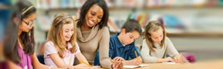 Image of a teacher working with students at a desk