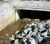 Photo showing a concrete drain with cut landscaping stones near the entrance.