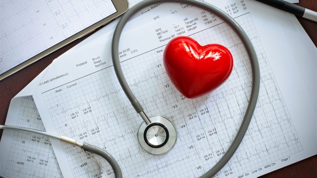 A stethoscope around a toy heart on top of charts 