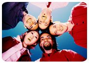 Photo of 5 people looking down and putting there heads together with a blue sky behind them.