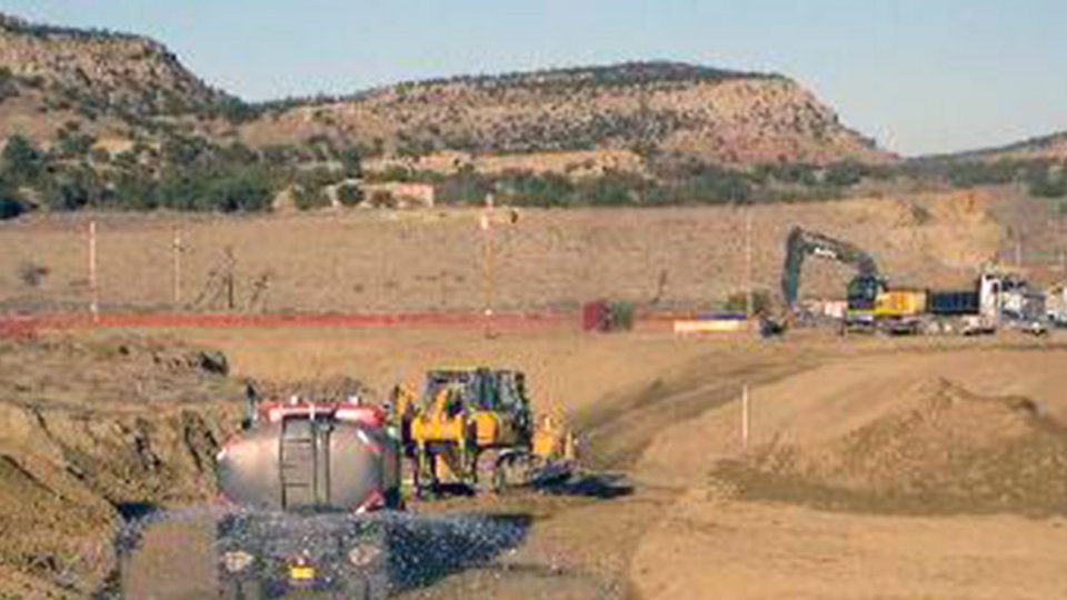 Earth movers and water truck wetting road surface