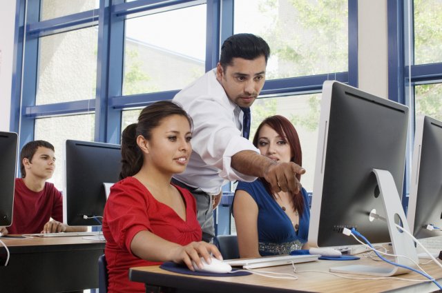 Picture of a teacher in a classroom assisting students with their coursework