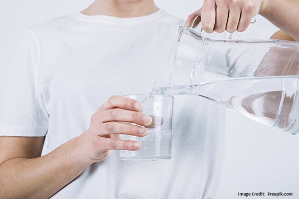 midsection crop pouring water from pitcher to glass