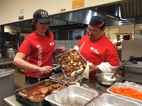 this is a picture of two kitchen volunteers packing up food for donation