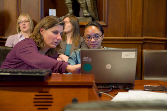 Two women looking at a computer screen; one points to the screen while the other looks on.