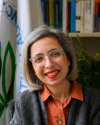 Elina Bravve in front of the EPA flag and a bookcase.