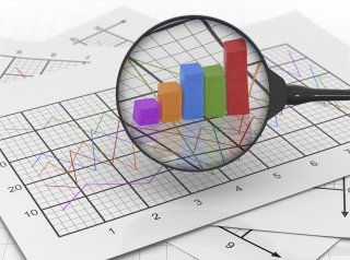 Stock photo of a magnifying glass zooming in on a bar graph and line graph