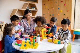 children at daycare around a table with a teacher