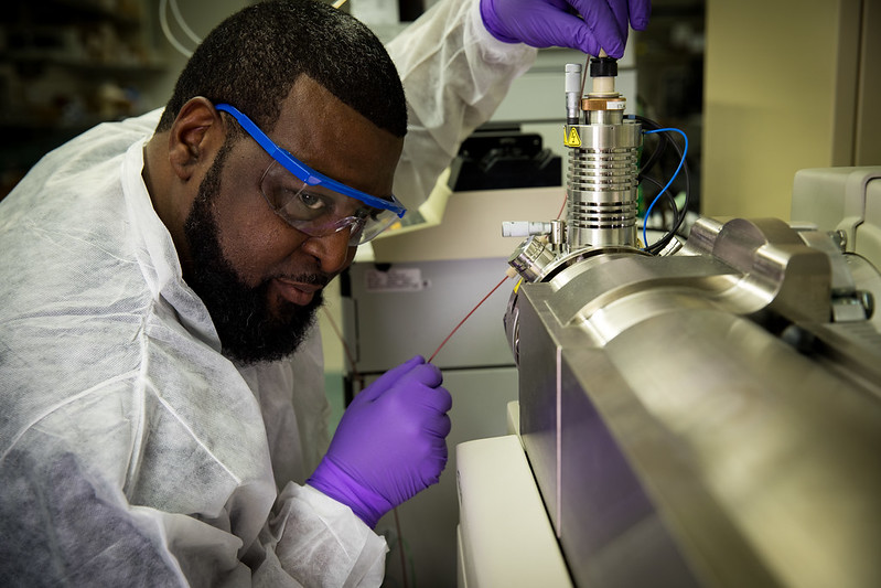 A person wearing lab gear inspecting lab equipment