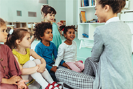 small children sitting on the floor with their teacher