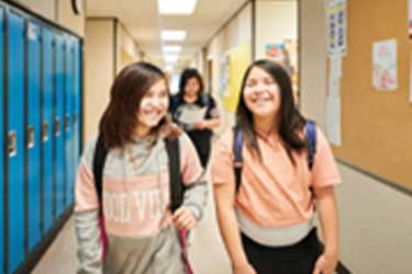 two native American girls walking together in a school hallway