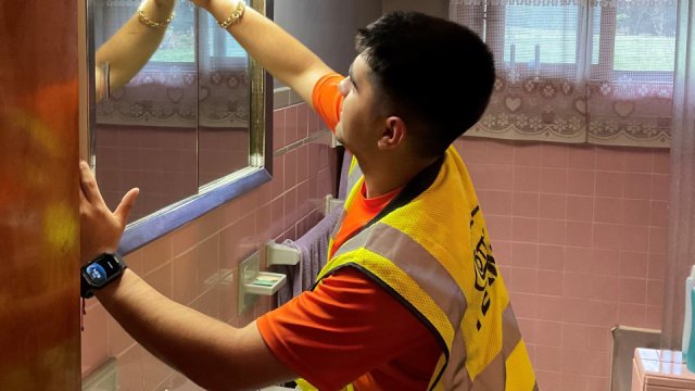 Person cleaning the mirror insode a bathroom of a residential property