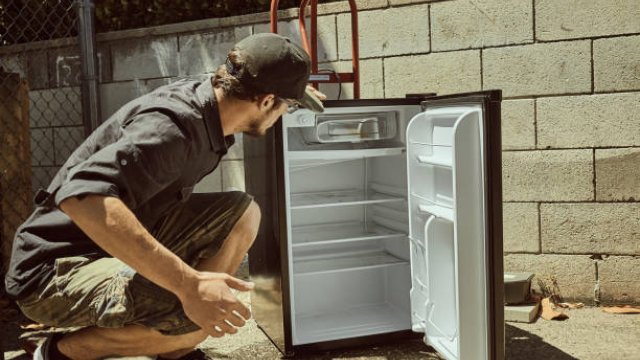 Man looking at empty mini refrigerator