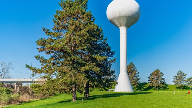 White water tower with trees and grass