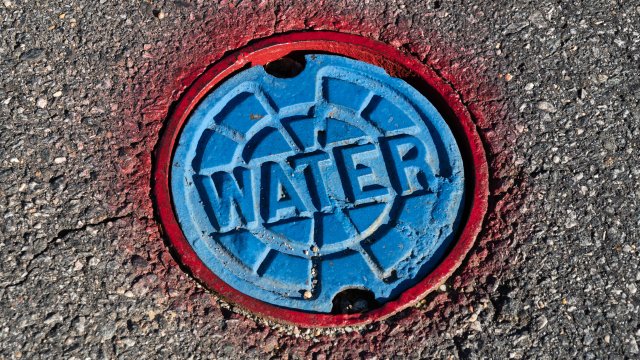 Red and blue water access point in the asphalt