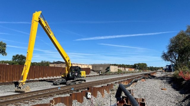 Large machinery near the train tracks with a clear blue sky.