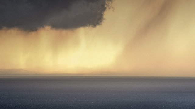 Landscape of rainstorm over the ocean at sunset.