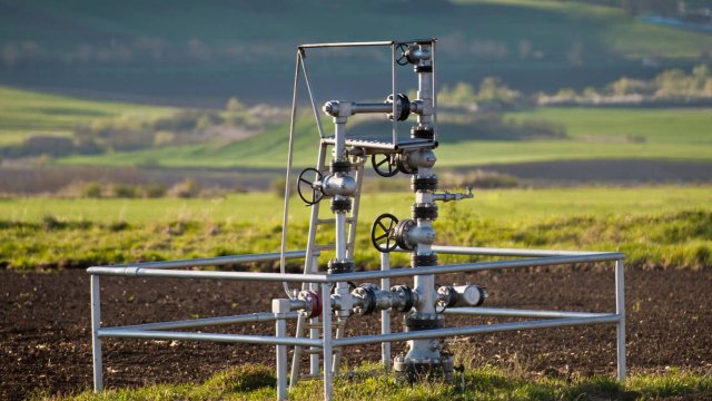 Wellhead at an oil and gas facility with fields in the background