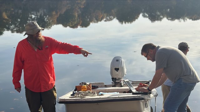 Researchers stand in front of a boat