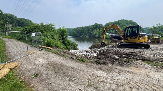 An excavator places stones that will create an equipment launching pad for water access.
