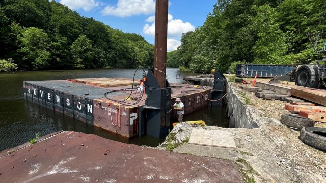 The crew installs spuds onto the dredging barge.