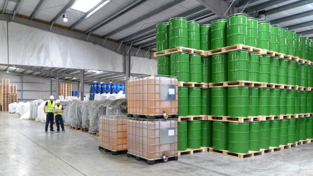 Workers inspecting pallets and containers of chemicals