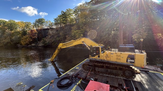 Platform floating on water with construction equipment on top.