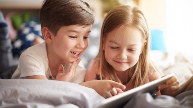 Two children on a bed reading a book
