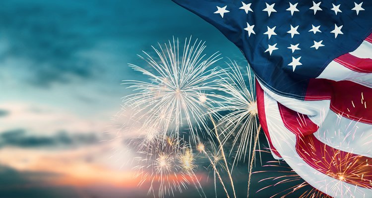 US flag unfurled with exploding fireworks in the sky