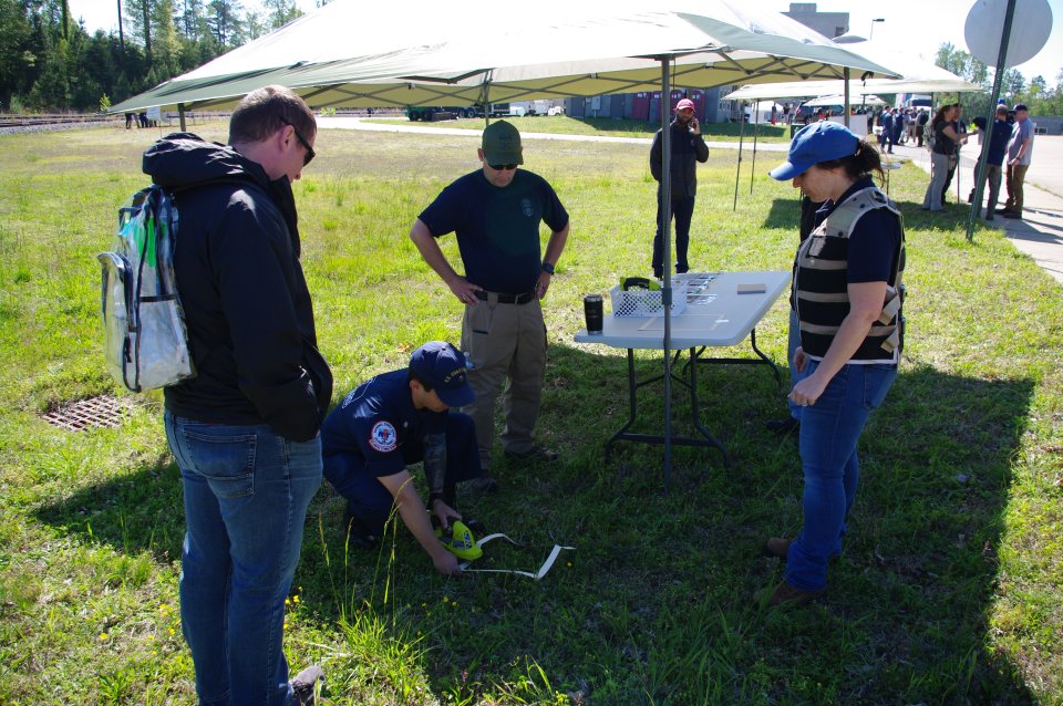 Four team members with three standing watching a fourth member take a sample of the grass.