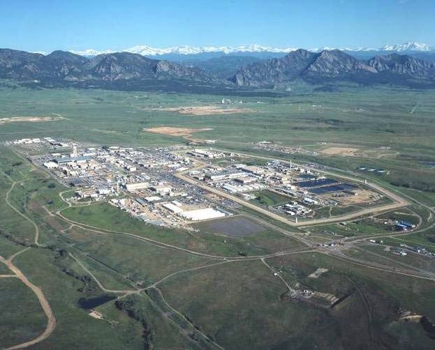 An aerial image of the Rocky Flats Plant (USDOE) site, with mountains in the background.