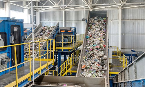 Materials flow down a metal chute inside a recycling facility.