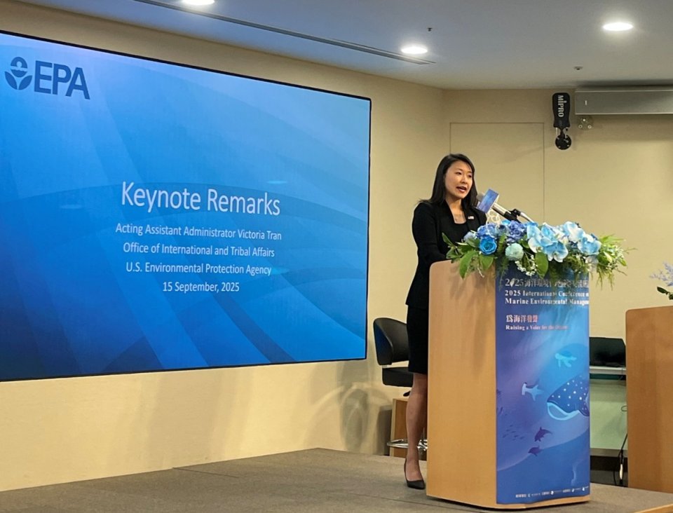 Then Acting Assistant Administrator giving remarks in behind podium and in front of presentation screen.