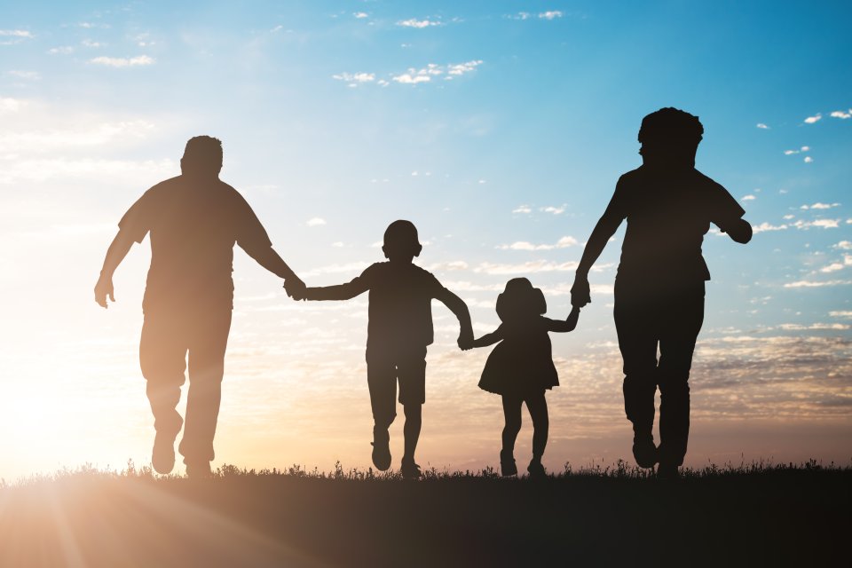 Family running outside towards a sunset