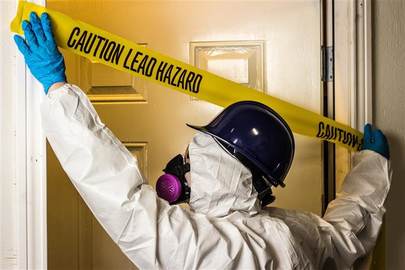 A contractor puts lead hazard tape over a door
