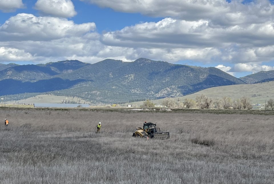 Workers conducting a sampling event under blue sky with clouds and mountains in the background
