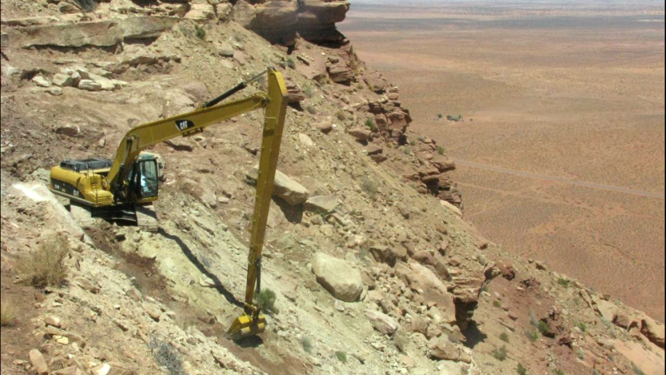 Excavator working on a steep desert slope.