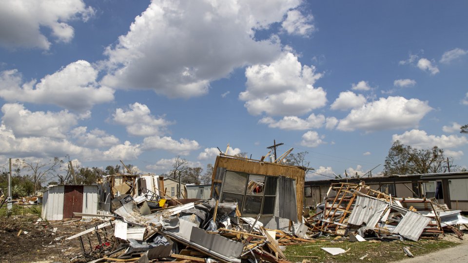 The aftermath of a storm - building debris and the remains of destroyed trailers are scattered about a trailer park. 