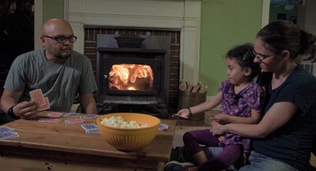 Family playing cards in front of a fire in a woodstove