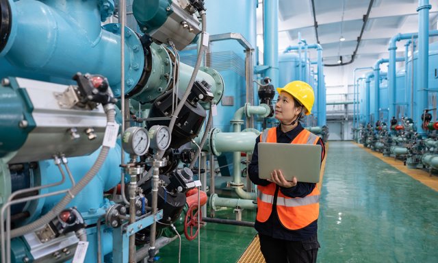 Woman inside industrial facility inspecting machinery