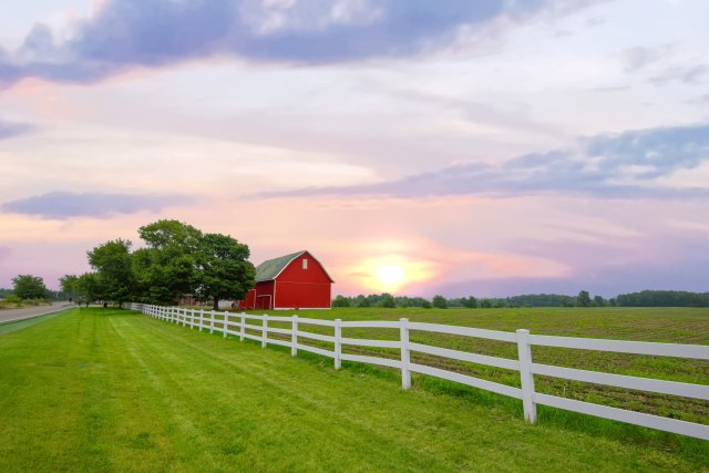 Red barn in field at sunset