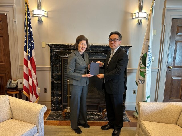 Acting Deputy Administrator and Japan Vice Minister standing in front of fireplace between US Flag and EPA Flag.