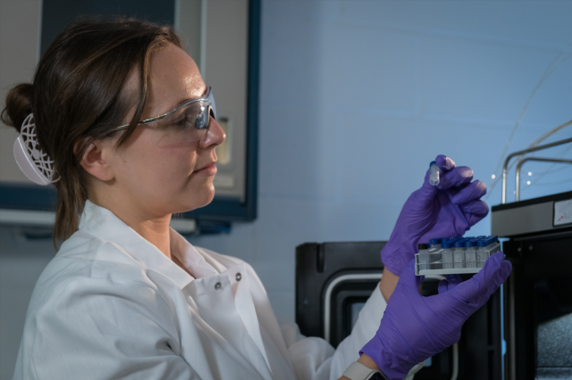 EPA researcher Anna Robuck wears personal protective equipment while examining samples.