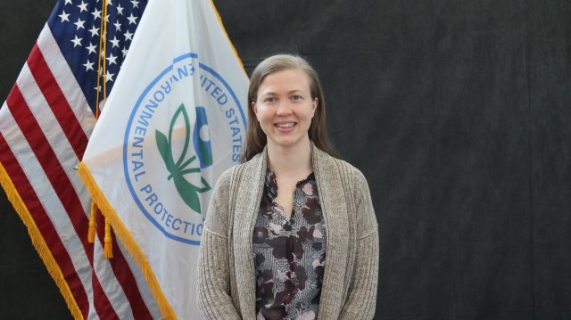 EPA researcher Karoline Barkjohn smiling in front of the EPA and American flag