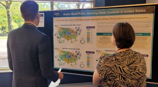 Two workshop participants pacing a poster board looking at a poster of U.S. maps.