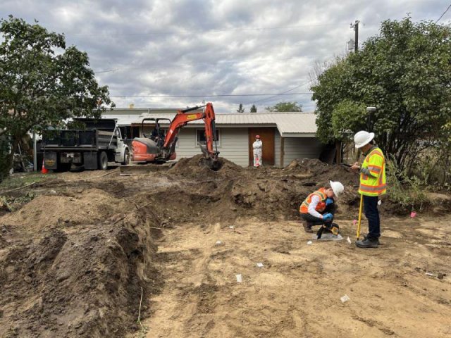 Workers excavate a large section of contaminated soil from a residential yard.