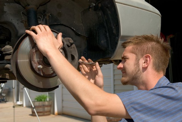 man working in the wheel well of a car