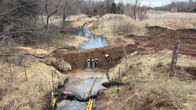 "Before" image of an underflow dam, used to separate oil from water, operating on the Chikaskia River. The river stream contains visible oil in this photo.