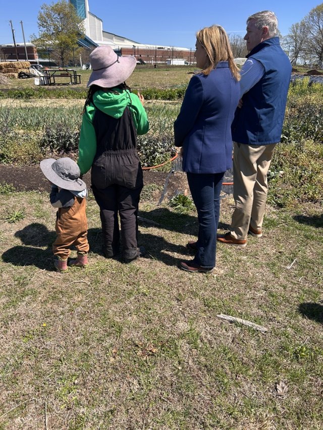 Officials and Farmer stand looking at farmland.