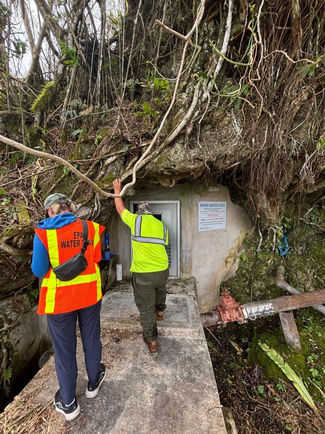 EPA staff walking into a drinking water building on a mountainside in Rota.